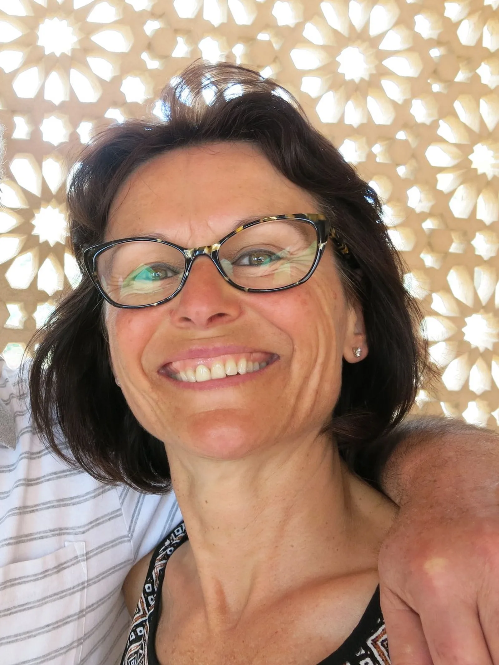 Brigitte, Kursleiterin in der Buitig, lachend vor einer hell gemusterten Wand