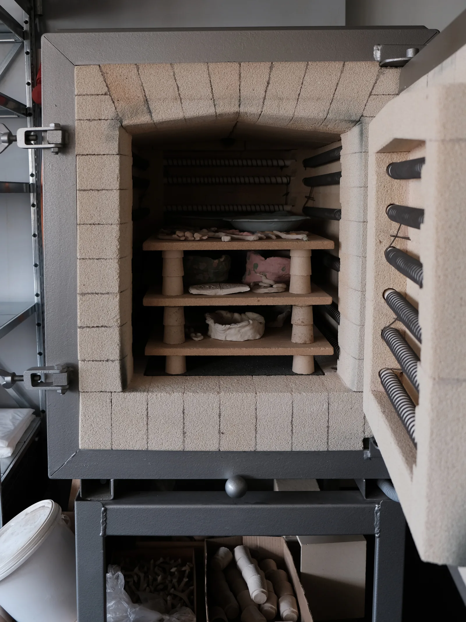 Geöffneter Brennofen mit Schamottsteinen und Einlegeplatten voller Keramik