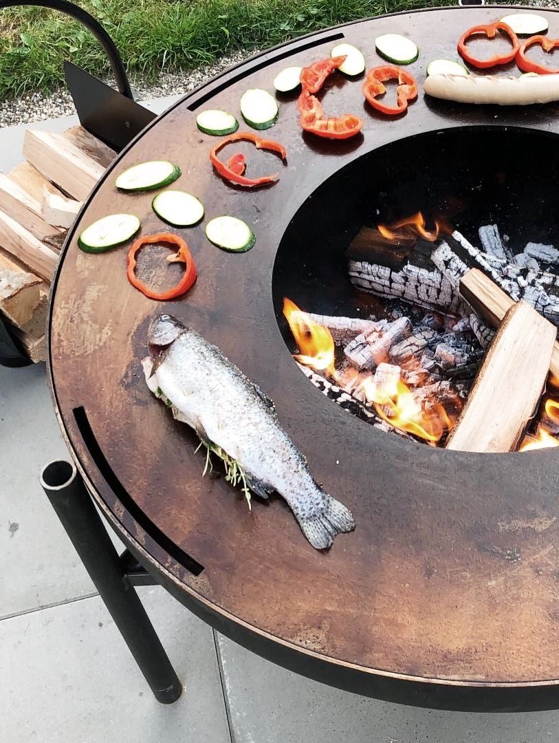 Feuerschale mit Gemüse und einem Fisch auf dem Grillring