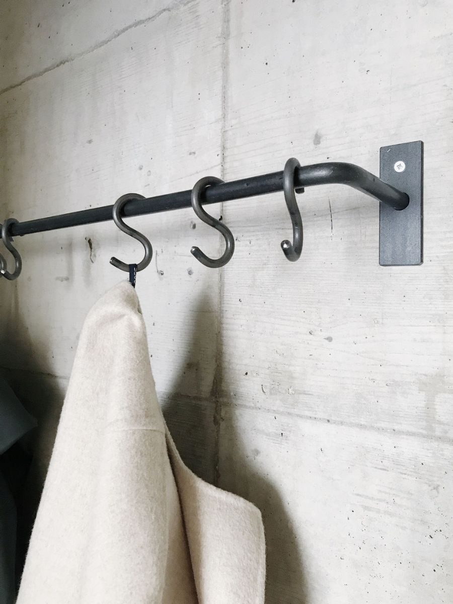 Garderobenstange mit angeschweissten Haken an der Betonwand, Nahaufnahme
