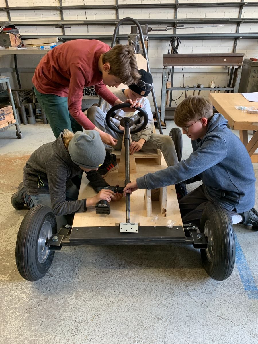 Zwei Jugendliche montieren die Lenkung des Holzwagens