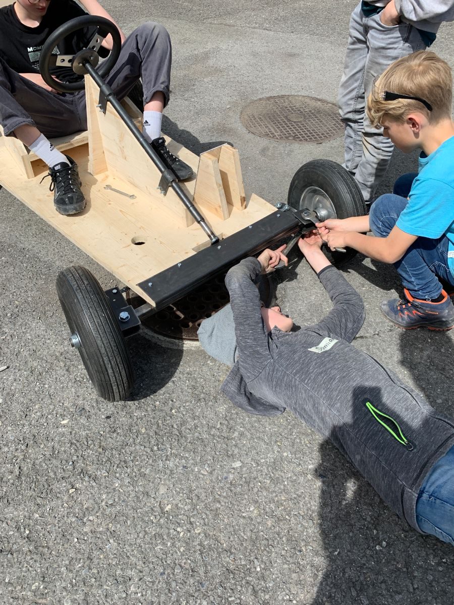 Kinder montieren ein Rad am Holzwagen
