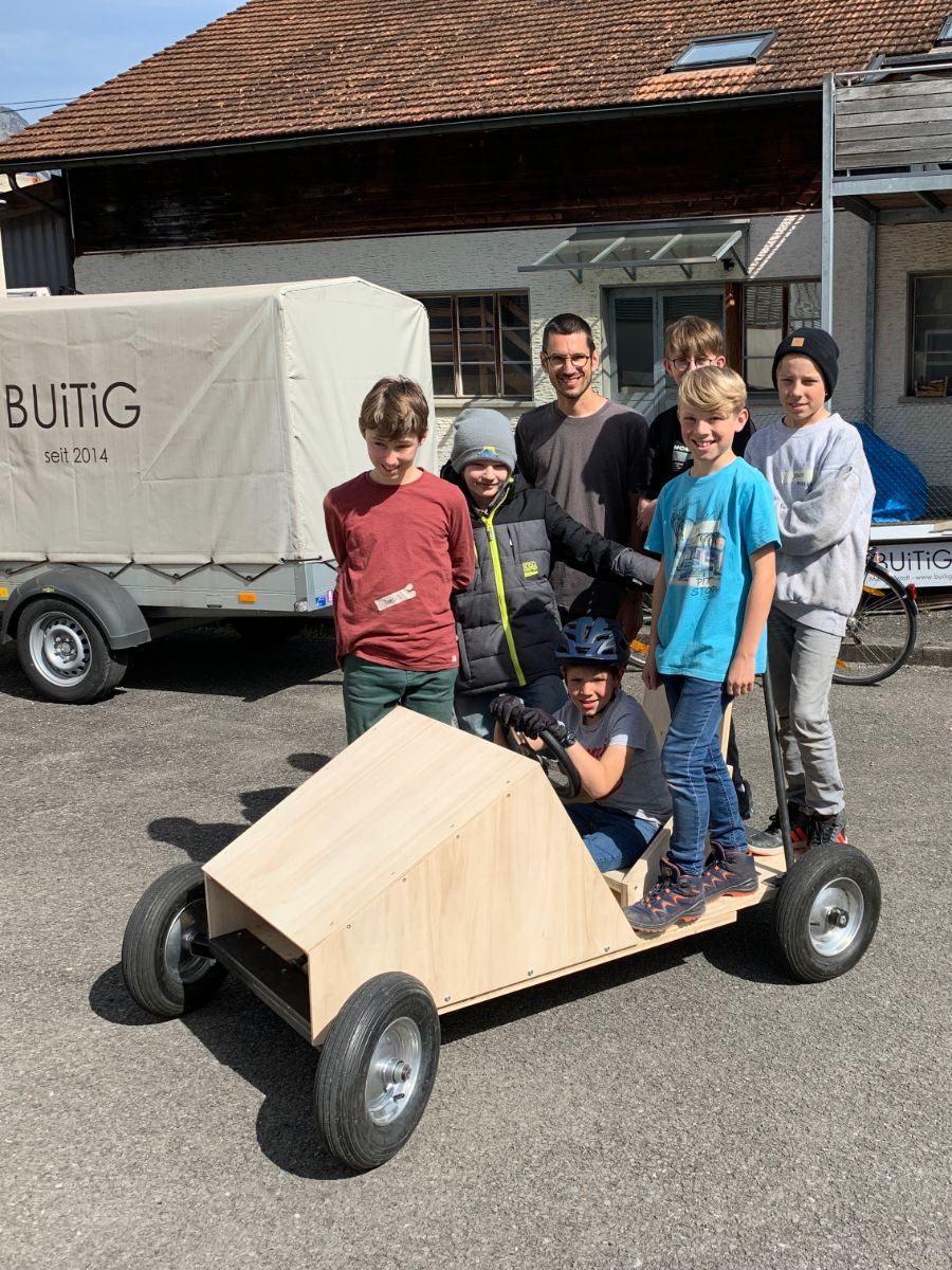 Gruppe von Kindern mit einem selbst gebauten Holzwagen vor der Buitig